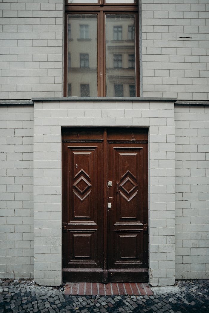gallery-2 Detailed vintage wooden door with geometric design in a classic urban building facade.